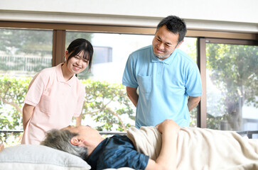 高齢者をベッドで介助する男女の介護士