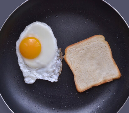 fried egg and bread on cooking pan.