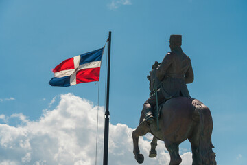 Closeup shot of the General Gregorio Luperon statue and the flag of Dominican Republic - obrazy, fototapety, plakaty