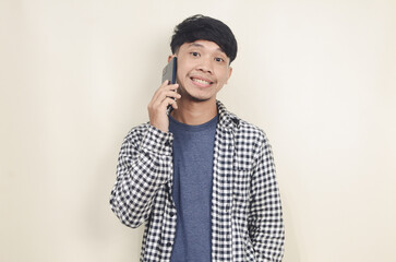 Close-up portrait of young Asian male model wearing plaid shirt talking on phone