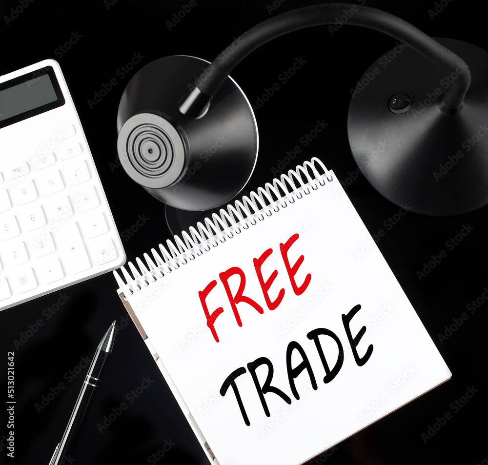 Poster opened paper notebook with text free trade with a pen, calculator and table lamp on black background