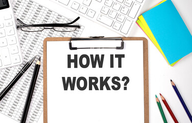 Clipboard with text HOW IT WORKS and keyboard and chart on white background.
