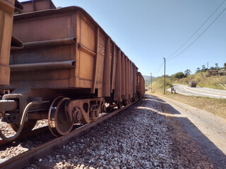 Fototapeta na wymiar Landscape showing empty train cars above tracks with side road and clean blue sky background at Itabira Minas Gerais Brazil 
