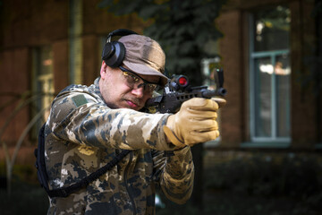 Cadet training course, man with gun in military uniform tactical hearing protector headset....