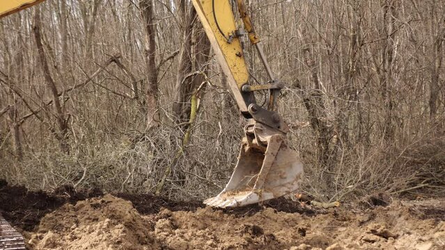 Working with backhoe by digging ground at construction site. Excavator bucket teeth for delve soil. Digging crawler dredge on soil. Digger. Earthmoving vehicle. Close up