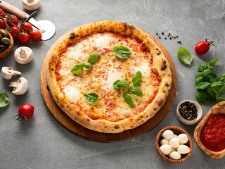 Pizza Margherita and ingredients on stone background