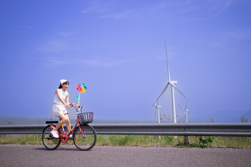 woman on vintage bicycle with on the background huge windmill turbines, windmill park green...