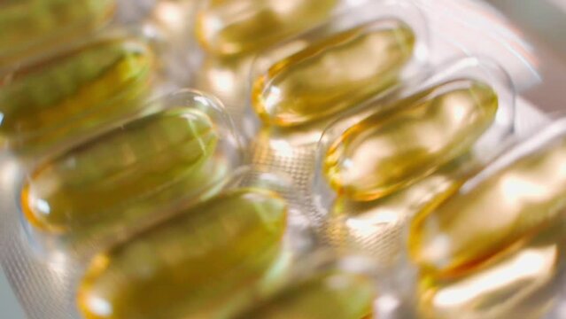 Foil plate with fish oil capsules close-up twirl