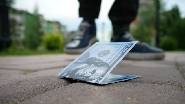 A walking man finds a hundred dollar bill on the sidewalk