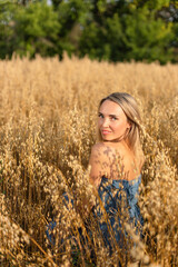 Fototapeta na wymiar Ukrainian beautiful woman in a blue dress in a yellow wheat field