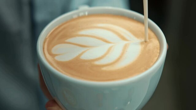 Barista making latte art in specialty coffee shop. Professional man making pouring stream milk with espresso
