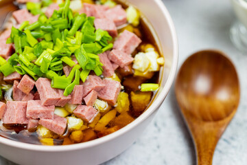 Okroshka - russian national food with meat, potato, kvass or kefir, radish and parsley on white background