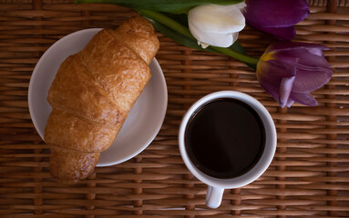 Cup of coffee, tulip, croissant in the room