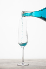 Single glass with blue champagne and a bottle on a white background. New Year or Christmas concept.