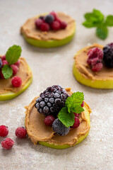 Healthy snack. Green apple rounds with peanut butter and berries