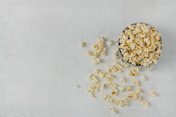 Fototapeta na wymiar A bowl of delicious popcorn on a light background, top view, copy space