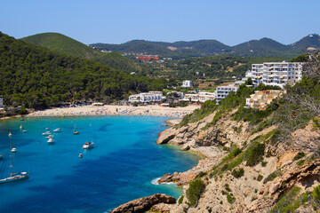 Fototapeta na wymiar Cala Llonga bay on the southern side of Ibiza in the Balearic islands in the Mediterranean Sea - Cove with turquoise waters surrounded with pine covered hills