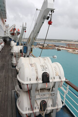Life rafts on board a cruise ship Upwards view of three lifeboat capsules against a blue cloudy sky...