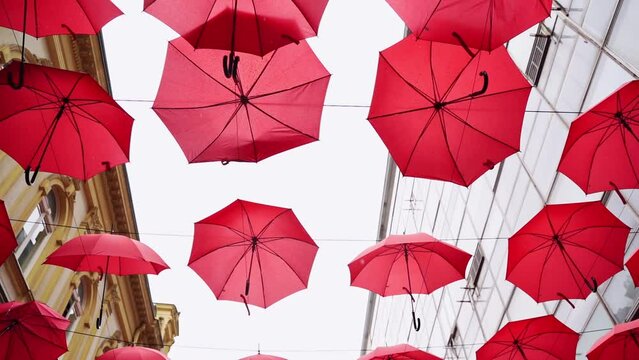Red umbrellas instalation on city street. Town Attraction for tourist. Outdoor activity. Freedom travel in Europe.