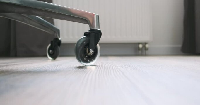 Office chair rolling on the floor. Close-up on silicone silent wheels. Side view.