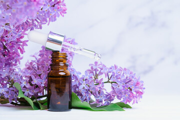 Lilac flowers and essential oil in a glass bottle with a pipette, copy space