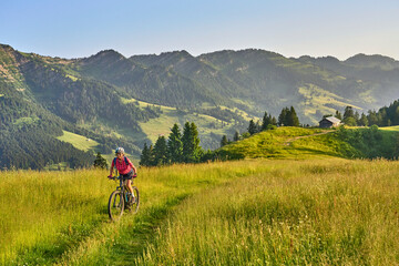pretty senior woman riding her electric mountain bike on the mountains above Oberstaufen with...