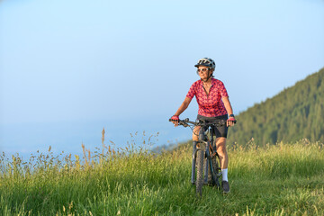 pretty senior woman riding her electric mountain bike on the mountains above Oberstaufen with...