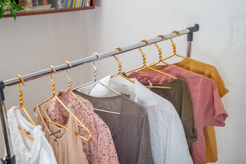 Second-hand clothes  on the rail on a light background. The concept of sustainable economic life. Copyspace