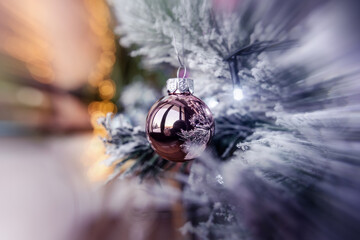 Rose gold pink glass Christmas ball bauble, snowy tree branch, golden bokeh bg