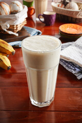 A glass of healthy fresh banana milkshake isolated on wooden background side view