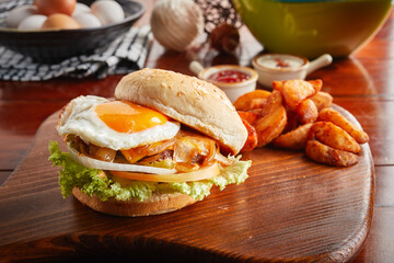 Beef Burger with sunny egg, fries and Caramelized onion served in a dish isolated on wooden background side view