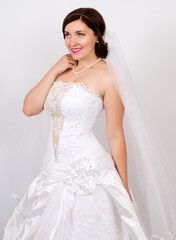 Young girl in a wedding dress with flowers on a light background