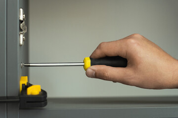 Hand of furniture maker uses a screwdriver to connect pieces of furniture. New furniture assembling concept
