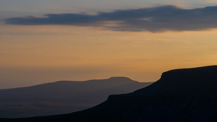 Sunsets of the distinct silhouette of Penyghent one of three hills that make up the Yorkshire 3 Peaks with its sister in the background Ingleborough