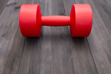 Obraz premium One red dumbbell on dark gray wooden surrface