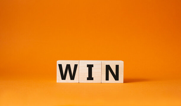 Win symbol. Wooden blocks with words Win. Beautiful orange background. Business and Win concept. Copy space.