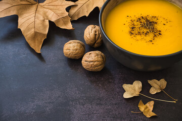 Autumnal composition with dried leaves and delicious creamy homemade vegetables soup on dark background