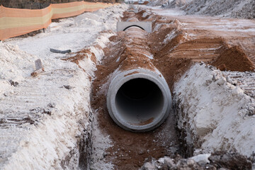 Laying sewer Concrete drainage pipe between large residential areas. New sanitary sewer, storm drain systems on construction site.