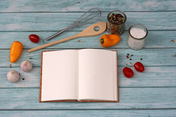 Leeres Rezeptbuch mit Gemüse und Gewürzen auf einem alten blauen Holzhintergrund.