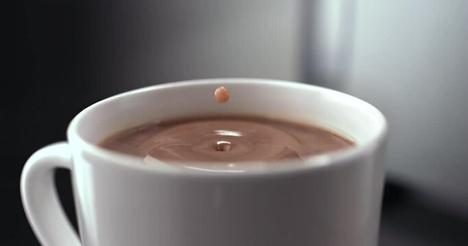 Super slow motion of coffee drop falls into a cup. Hot chocolate, espresso, or americano. Filmed on a high-speed cinema camera, 1000 fps