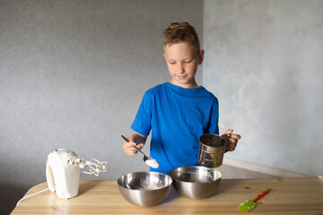 The child prepares dough in metal bowls and looks away . Pour flour