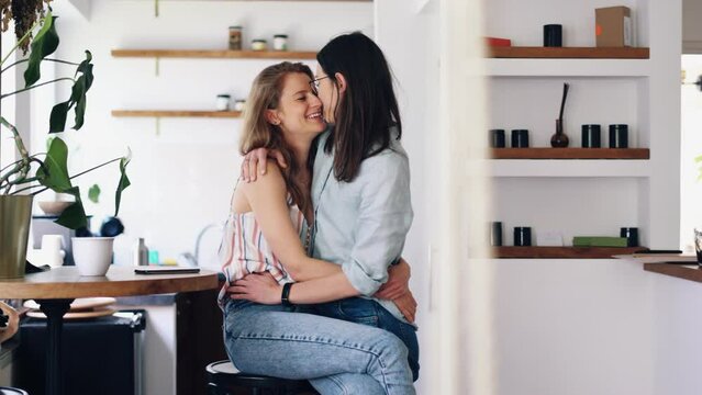 Young lesbian couple embracing and kissing at home
