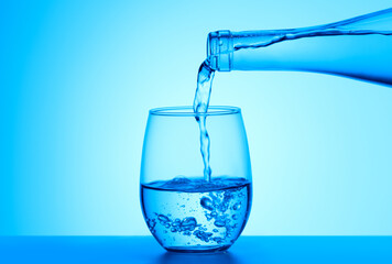 Crystal clear water pouring into the glass on a blue background. Quality water for your health...