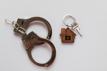 House with key and handcuffs on the table. Fraud in real estate concept