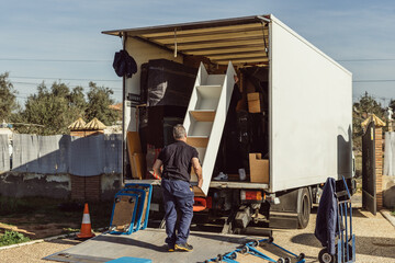 gray-haired man loading furniture onto a moving truck