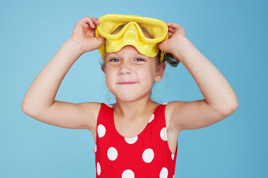 Happy child girl in yellow scuba mask. Funny face on blue background