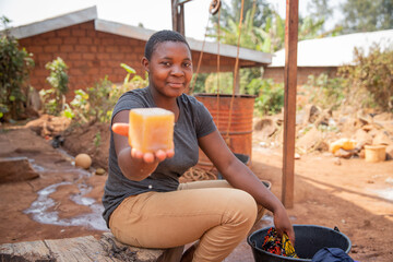 Close-up of the laundry soap held in the hand by an african girl while washing clothes in her garden