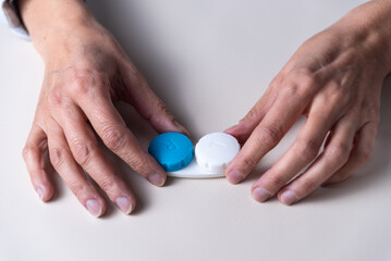 two woman's hands with contact lens case, copy space, myopia and astigmatism, vision concept, selective focus
