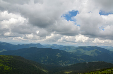 Fototapeta na wymiar Low cloudy sky over the mountain peaks covered with dense forest. Carpathian mountains, Ukraine. Travel background.
