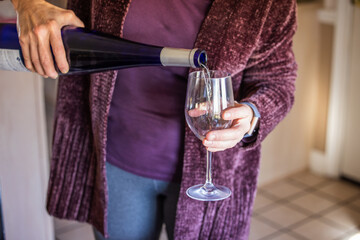 A woman in the winter pouring a glass of white wine